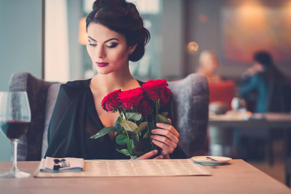 la femme est assise seule avec un bouquet de roses à la main