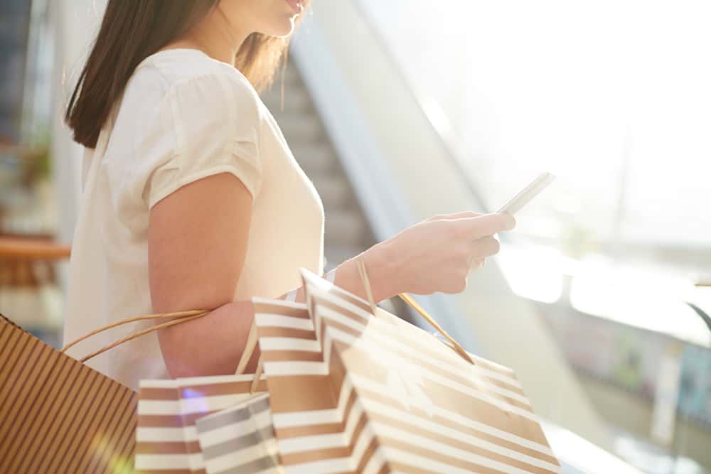 la femme revient des achats et des boutons sur le téléphone
