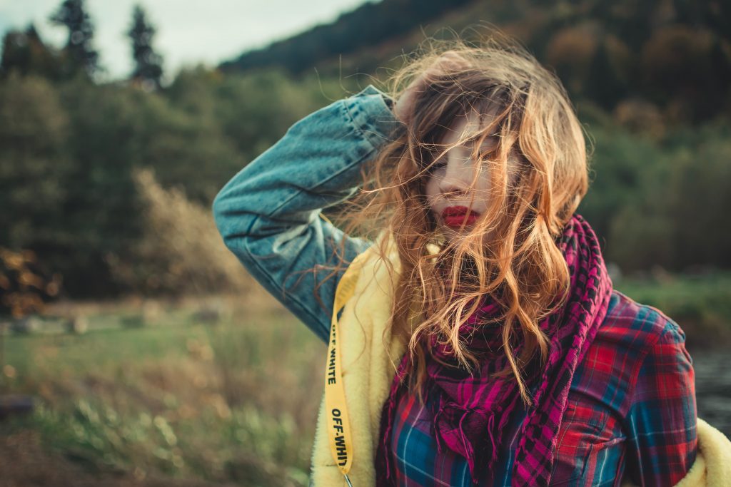 la femme se tient avec sa main levée dans ses cheveux