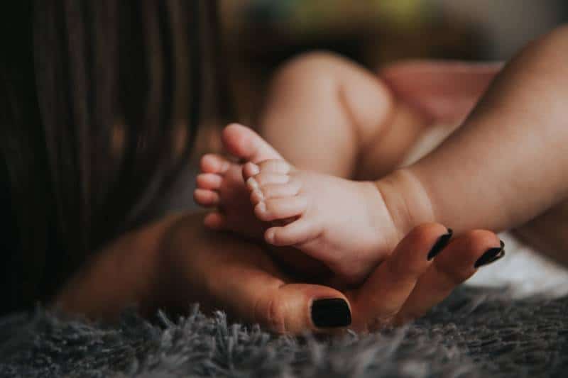 les pieds du bébé tenus par une femme