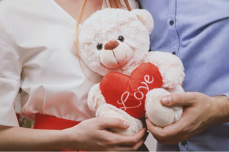 un homme et une femme tenant un ours en peluche avec amour coeur