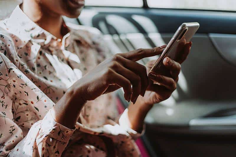 photo en gros plan d'une femme tapant sur son téléphone dans la voiture