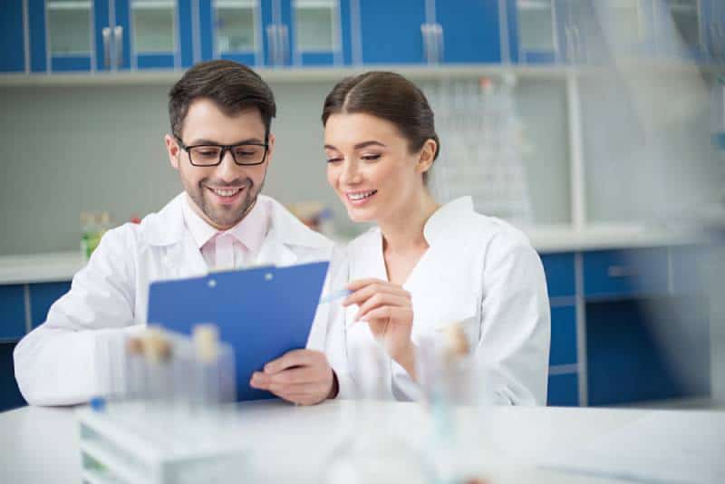 portrait de scientifiques souriants écrivant sur un bloc-notes dans un laboratoire