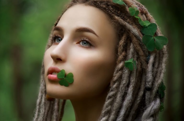 un portrait d'une belle femme avec des trèfles dans les cheveux et la bouche