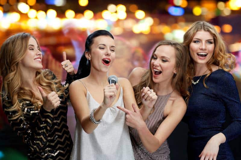 trois femmes en robe du soir avec micro chantant le karaoké
