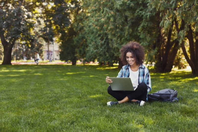 un étudiant avec un ordinateur portable assis sur l'herbe