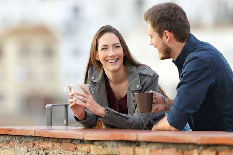 un couple heureux qui parle dehors et boit du café