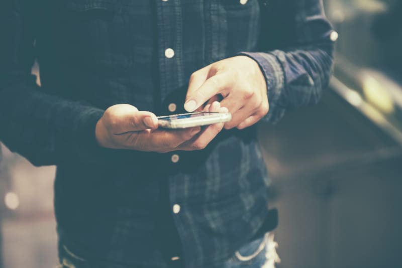 un homme en chemise bleue tapant sur son téléphone