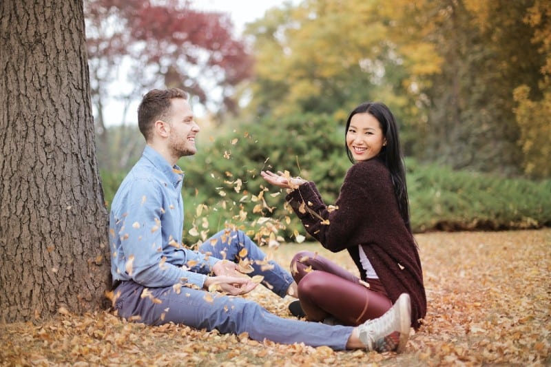 un homme et une femme assis sur le sol près d'un arbre face à face