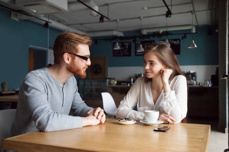 un homme et une femme se regardant et se parlant dans un café