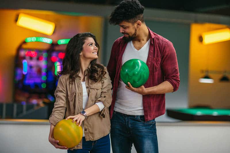 un homme et une femme se regardant et tenant une boule de bowling