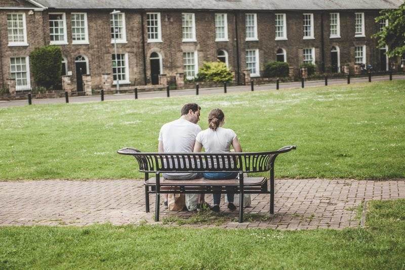 un homme et une femme sont assis sur un banc, le dos tourné