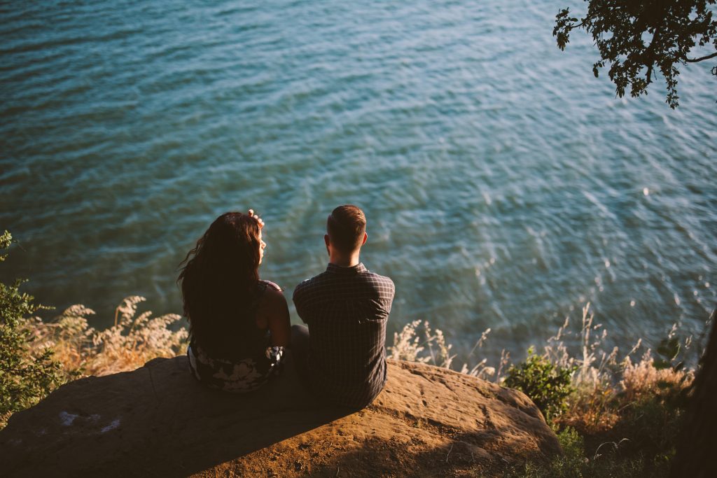 un homme et une femme sont assis sur une falaise