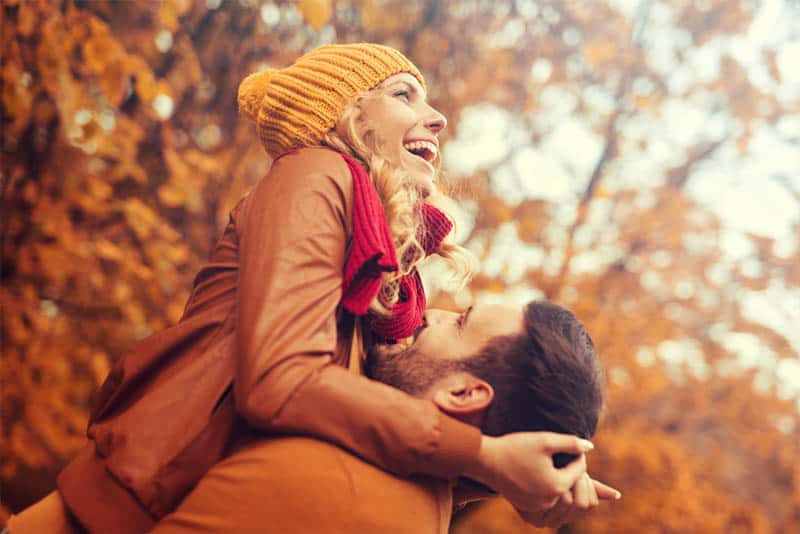 un homme heureux ramasse une femme en automne