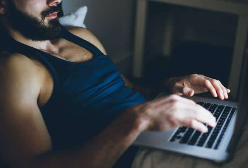 un homme tape sur son ordinateur portable avant de dormir