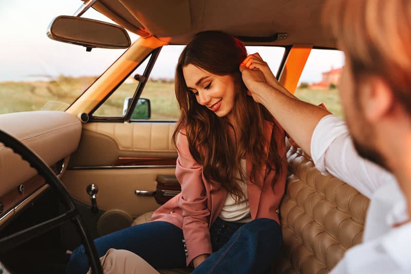 un homme touche les cheveux d'une femme en voiture