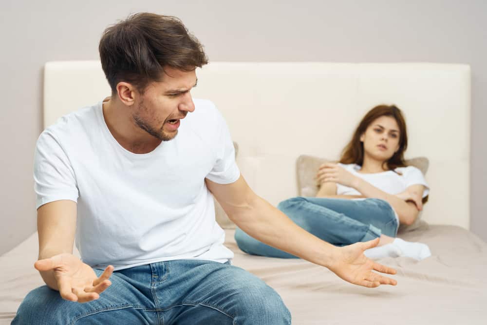 une femme allongée sur un lit un homme se disputant