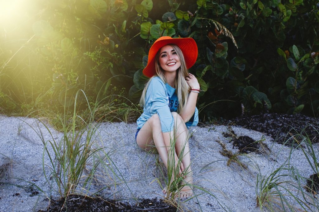 une femme avec un chapeau rouge sur la tête est assise sur le sable