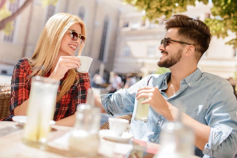 une femme parlant à l'homme sur une séance de café à une table en plein air