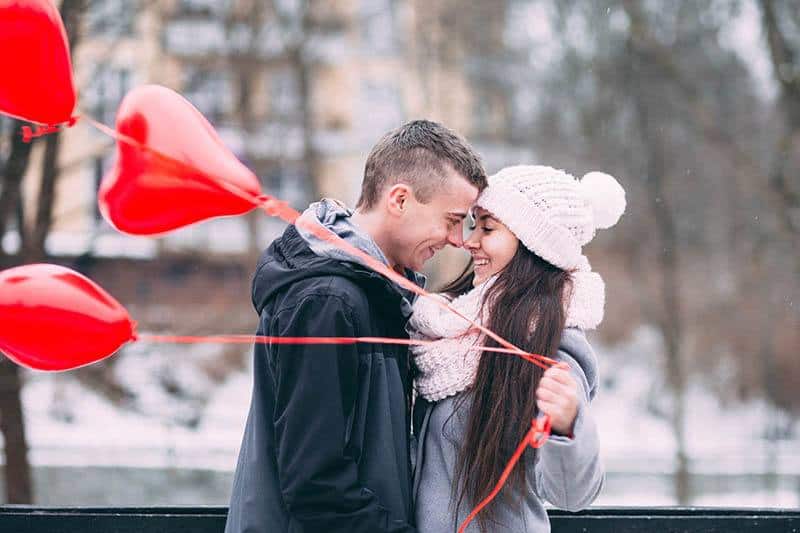 une femme tient un ballon en forme de cœur et embrasse un homme