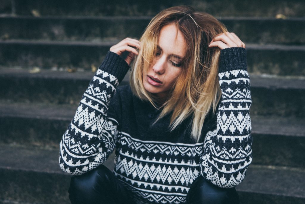 une femme triste est assise, la tête baissée