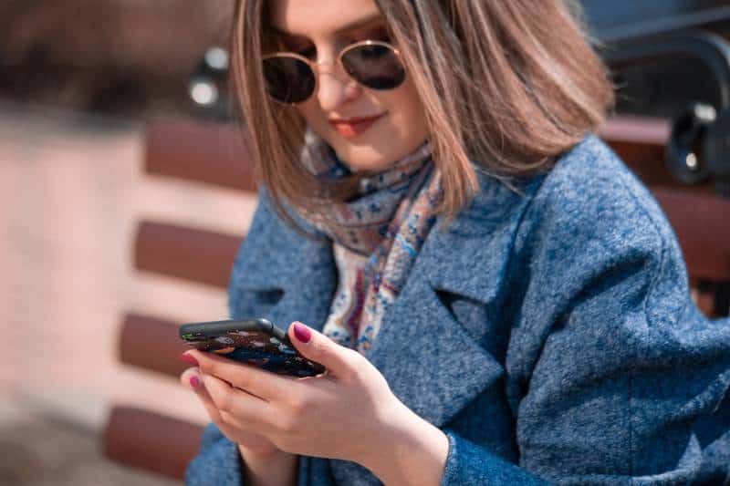 une fille tape un sms sur un banc de parc
