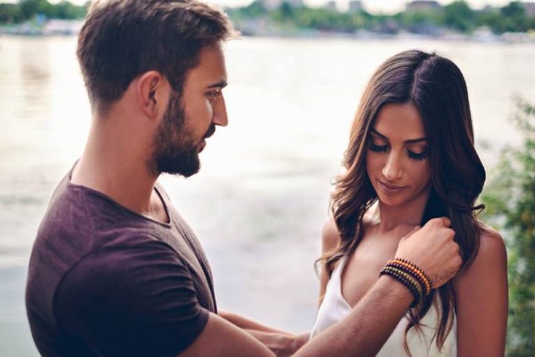 un homme touche les cheveux d'une femme au bord de l'eau