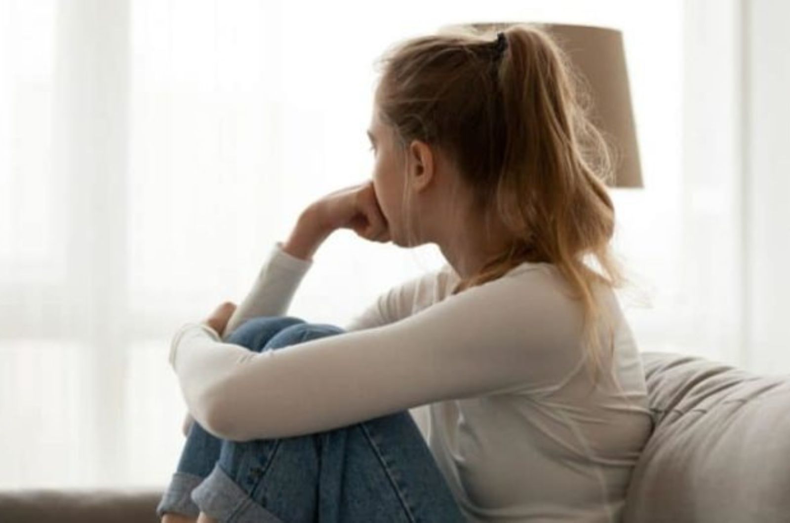 la femme est assise sur le canape en detournant les yeux