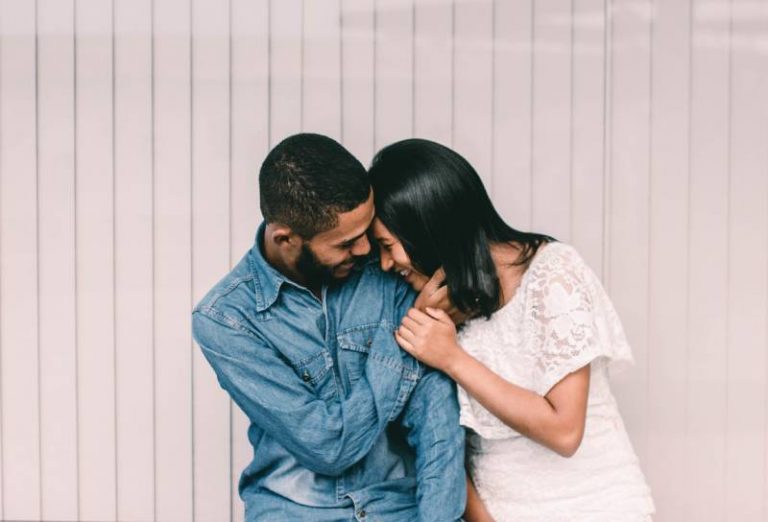 Un homme et une femme souriants devant un mur blanc et gris