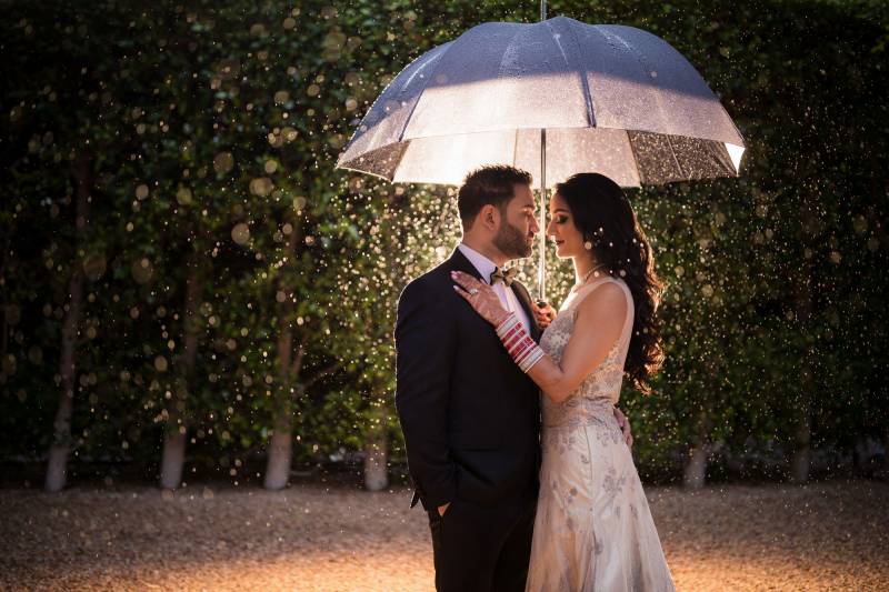Le marié et la mariée sous un parapluie blanc pendant la nuit