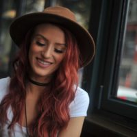 une femme rousse avec un chapeau est assise