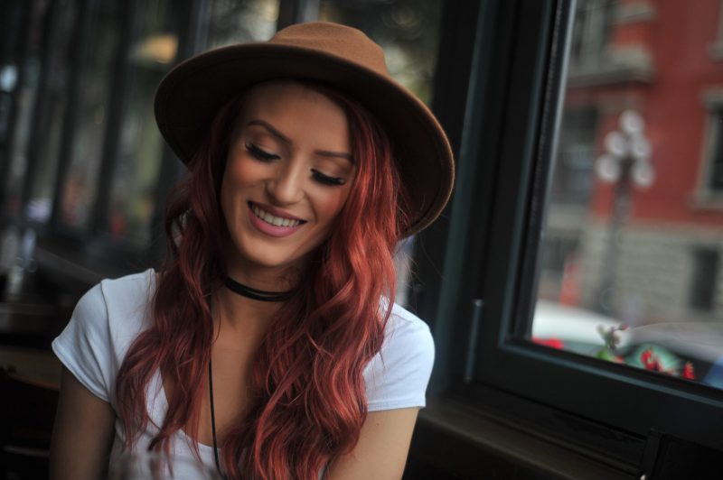 une femme rousse avec un chapeau est assise