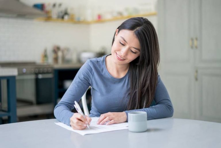 Une femme souriante écrit une lettre à la maison