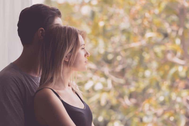 Un couple s'embrassant en regardant dehors à la maison en automne