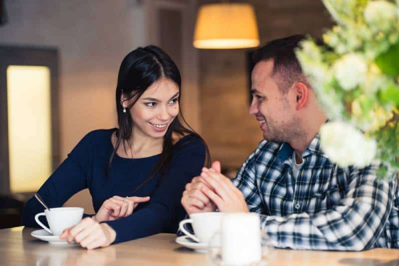 Un couple souriant se regarde dans un café