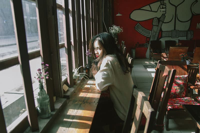 Une femme attentionnée assise à la fenêtre d'un café