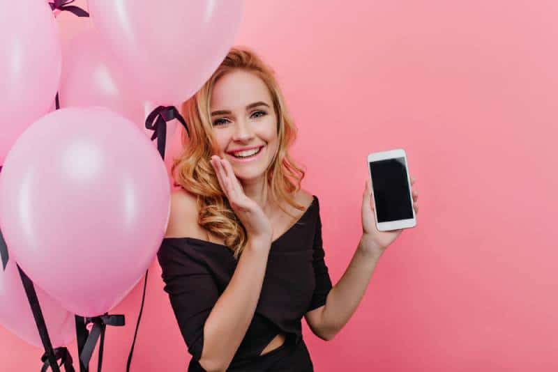 Une femme blonde à la mode reçoit un smartphone comme cadeau d'anniversaire.
