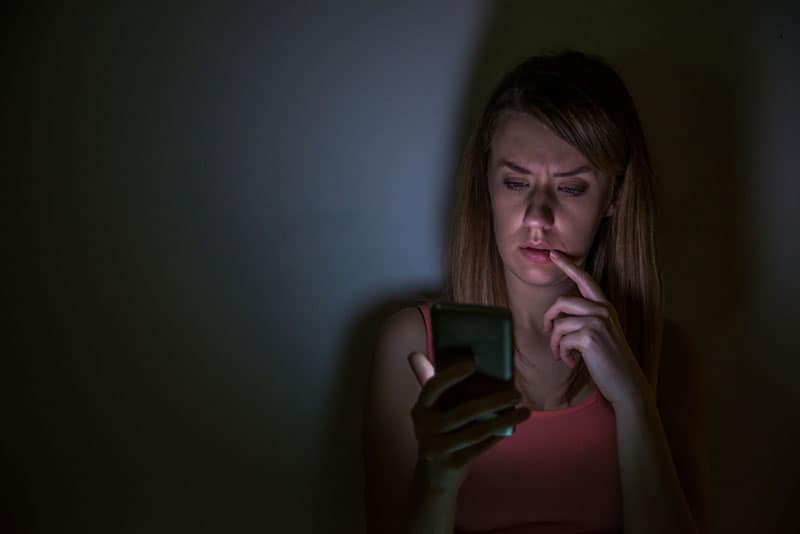 Une femme inquiète regarde son téléphone pendant la nuit à la maison
