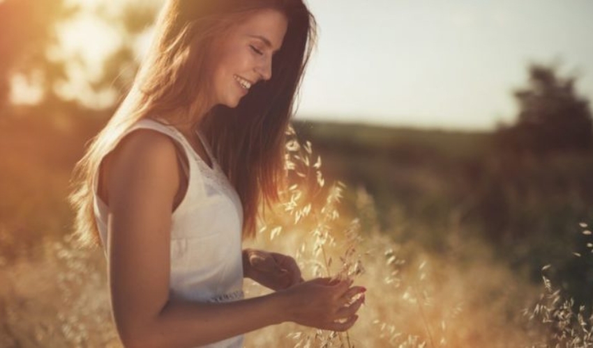 une femme se tient avec une fleur a la main