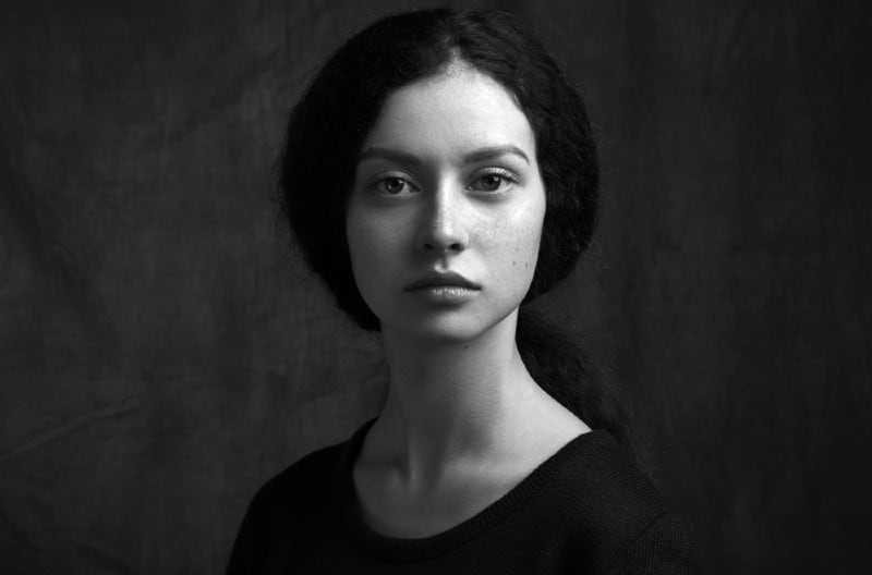 Portrait noir et blanc dramatique d'une belle fille solitaire avec des taches de rousseur isolé sur un fond sombre en studio shot