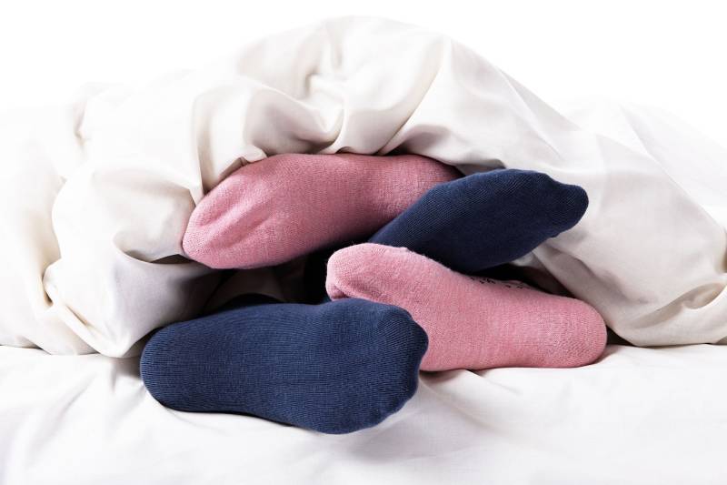 couple portant des chaussettes en étant allongé sur le lit