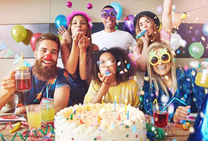 des amis qui célèbrent une fête avec un grand gâteau et des boissons sur la table au premier plan