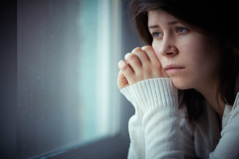 fille triste près de la fenêtre en pensant à quelque chose