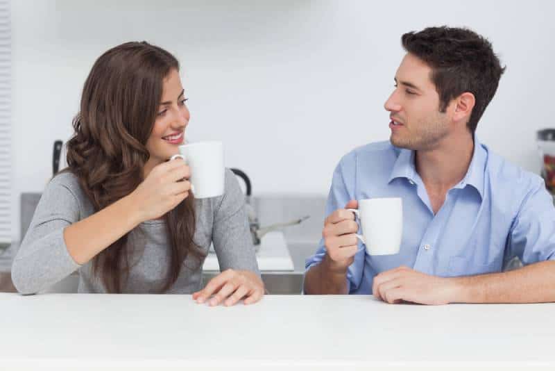 homme et femme parlant et tenant une tasse de thé blanc à la maison