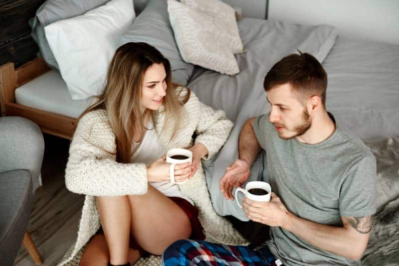 jeune couple discutant dans sa chambre avec un café