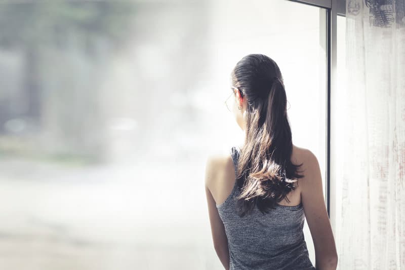 la femme regarde par la fenêtre