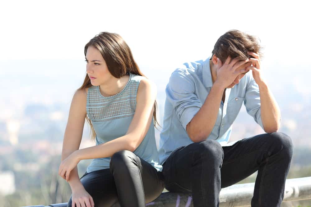 l'homme est assis à côté de la femme tenant sa tête