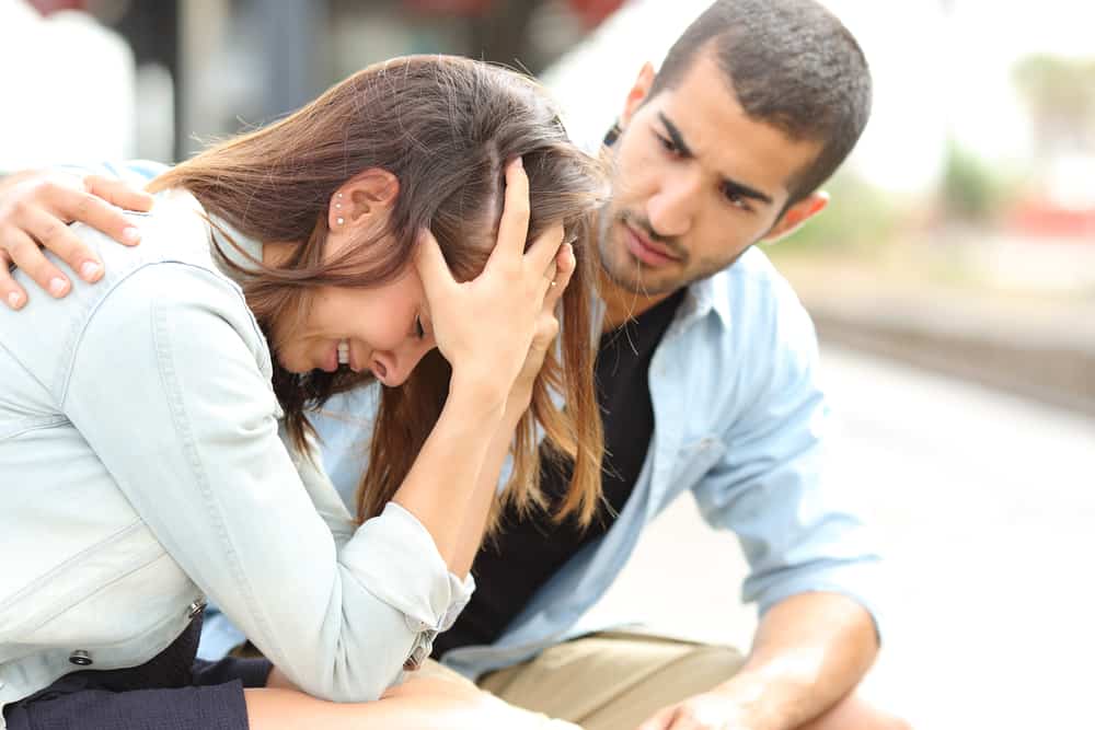 l'homme réconforte la femme alors qu'ils sont assis sur le banc et elle pleure