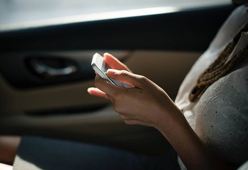 photo en gros plan d'une femme tapant sur son téléphone dans une voiture