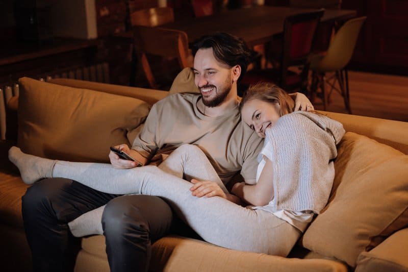 un homme et une femme sont assis sur le canapé et regardent la télévision